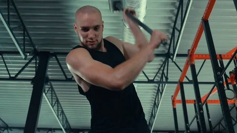 An athlete has a hammer on a big wheel. My husband trains in the gym. Stock Footage 112294151