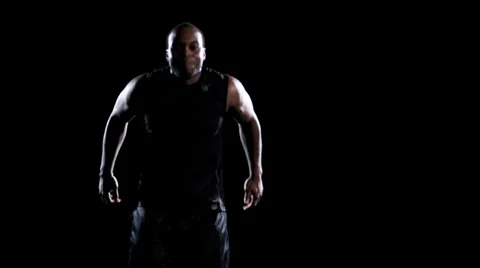 An athlete jumps up and down to get warmed up and ready in a dark room Stock Footage 33834225