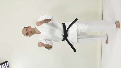 An athlete in karategi performs kicks and hand blocks in a vertical projection Stock Footage 246983835