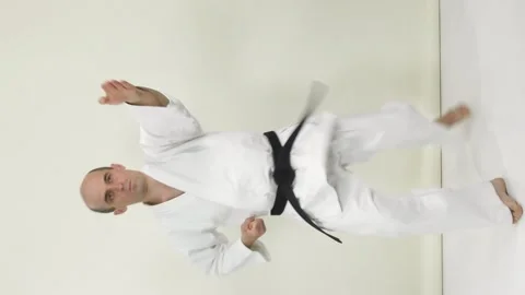 An athlete in karategi performs kicks on his hands in a vertical projection Stock Footage 246983834