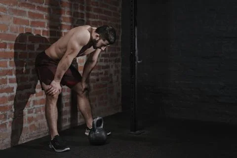 Athlete is leaning against the wall at the gym suffering breakdown to overcom Stock Photos