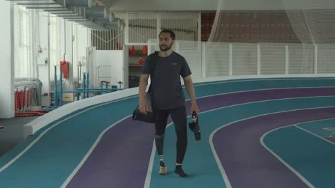 Athlete with Leg Prosthesis Walking on Indoor Track Vídeo Stock 259279128