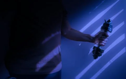 Athlete lifting dumbbell in dramatic blue light and shadows Stock Photos