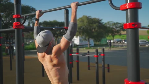 Athlete man does pull ups on horizontal bar outdoors Stock Footage 237249110