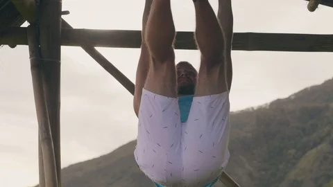 Athlete man doing abdominal exercise on wooden crossbar while outdoor gym Stock Footage 107135986