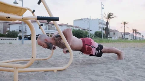 Athlete man doing push up with parallel bars in a calisthenics park at the beach Stock Footage 159639534