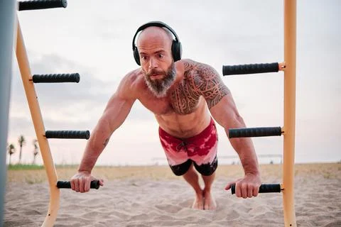 Athlete man doing push up with parallel bars in a calisthenics park at the beach Stock Photos