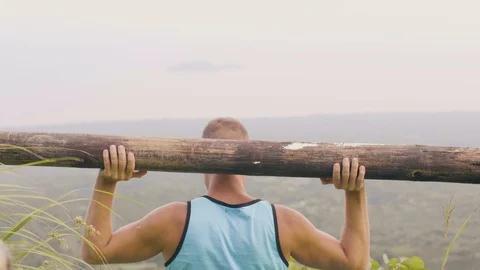 Athlete man training press exercise with wooden barbell on green mountain valley Stock Footage 107138645