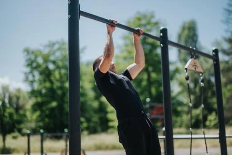 Athlete performing pull-up exercises outdoors in a lush green park setting Stock Photos