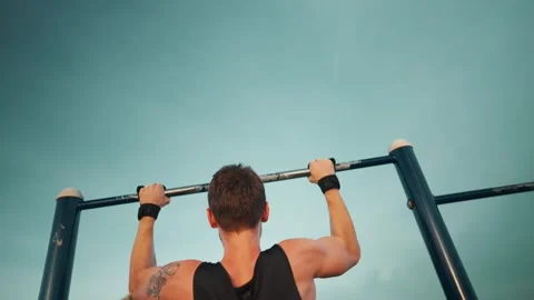 Athlete performing pullup on bar outdoors, showcasing strength and dedication Stock Footage 320223689