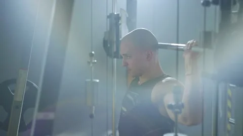 An athlete performs exercises with weights on a simulator in the gym. Stock Footage 239008295
