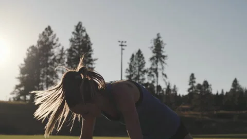 Athlete performs jump squats at sunrise on sports field Stock Footage 312719880