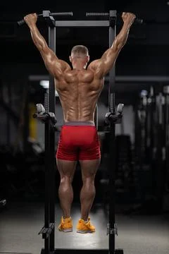 Athlete performs pull ups in gym during evening workout session for strength Stock Photos