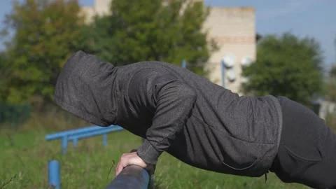 Athlete  performs push-ups from an iron bar. crossfitter trains in the stadium. Stock Footage 218467930