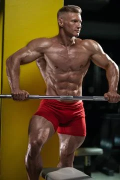 Athlete performs strength training in gym with a barbell while focusing on Stock Photos