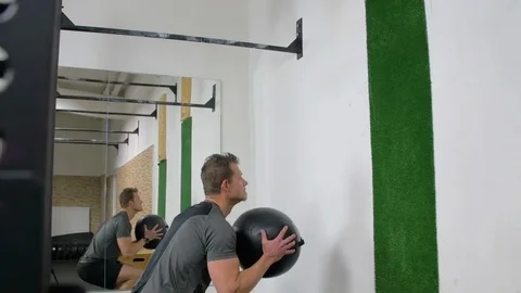 Athlete practicing wall ball shots with a med ball at the gym. Stock Footage 113356956