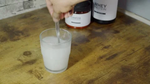 Athlete preparing creatine supplement drink with whey protein Stock Footage 313564674