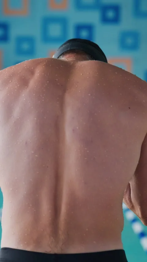 Athlete preparing swim, back view, water droplets, blue wall backdrop Stock Footage 346457788