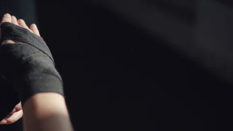 Athlete pulls on his wrists protective bandages before boxing training Stock Footage 104252694