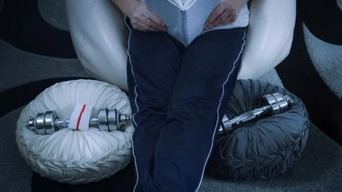 Athlete reading a book while resting after home workout session Stock Photos
