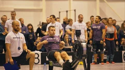 Athlete is rowing on a rowing machine. A judge stands near Stock Footage 58031749