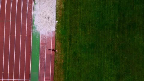Athlete running along the edge of a track field Stock Footage 293312100