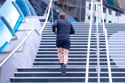 Athlete, running down the stairs, doing dynamic exercise outdoors Stock Photos