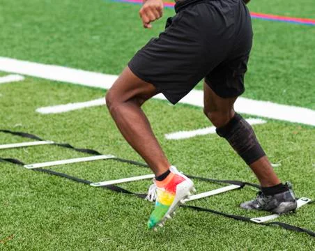Athlete running ladder drills on turf field in cleats Stock Photos