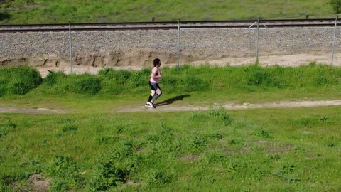Athlete running on a path next to a railroad Stock Footage 307101053