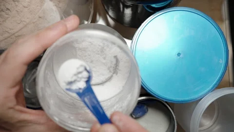 Athlete scooping pre-workout powder from a jar, preparing to add it to their Stock Footage 283783187