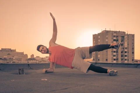 Athlete side plank exercise, Sun sunset sunrise, roof rooftop Stock Photos