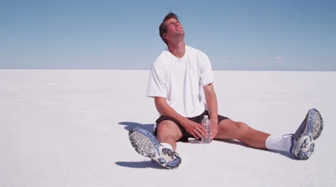 Athlete sitting down drinking water at salt flat Video stock 62281882