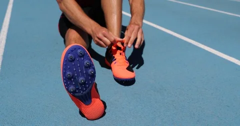 Athlete sprinter getting ready to run tying up shoe laces, stadium running track Stock-Footage 117933671