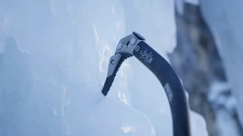 An athlete sticks an ice axe in an icefall to climb it, Alps, Switzerland Stock Footage 240173764