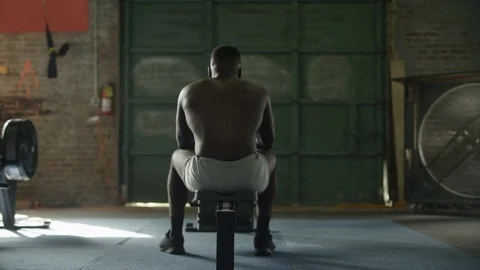 Athlete stretches while sitting on rowing machine in industrial-style gym Video stock 124456292