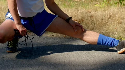 An athlete is stretching on the road while using a jump rope for training Stock Footage 318923413