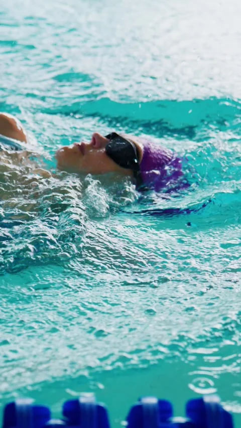 Athlete swims freestyle with powerful arm movements in turquoise pool Stock Footage 346457615