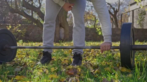 An athlete training with a barbell in the backyard of the house. Slow motion Video stock 252463527