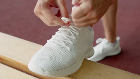 Athlete tying shoelaces before a workout. Tying a white sneaker on a bench .. Stock Footage 341457513