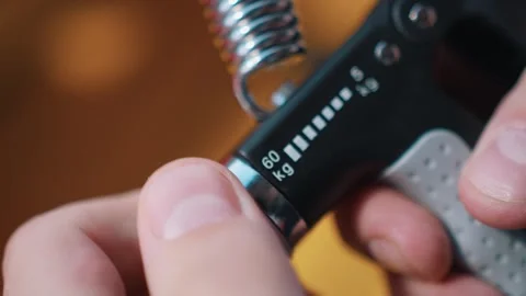 Athlete uses an hand expander. Guy trains sitting at stadium Video stock 260829580
