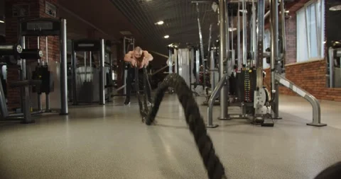 Athlete uses two ropes to train his upper body. He swings ropes rhythmic motion. Stock Footage 229852219