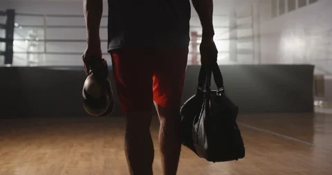 An athlete walking into a gym with a bag and boxing gloves, ready to start Stock Footage