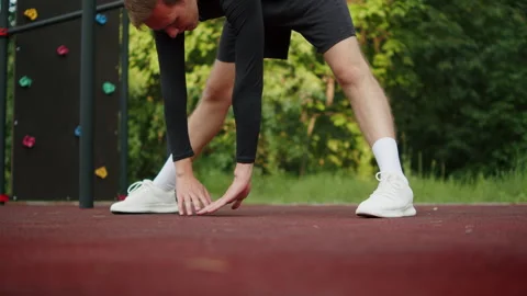 Athlete warming up on an outdoor training area. Man doing a wide-legged for.. 動画素材 341729639