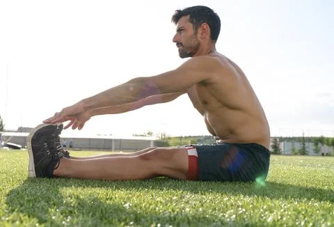 Athlete warming up by stretching before exercise Stock Photos