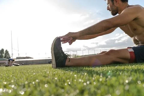 Athlete warming up by stretching before exercise Stock Photos