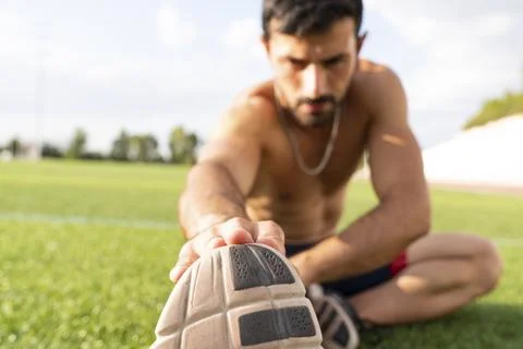 Athlete warming up by stretching before exercise Stock Photos