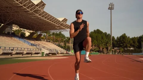 Athlete warms up as a runner by lifting his knees and jumping on a competit.. Stock Footage 267894473