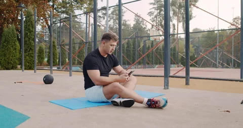 An Athlete Who Is Focused While Checking Their Phone During a Break in Their Stock Footage 318073674