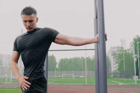 Athlete young guy does a warm up on the simulator. Stretching back muscles be Stock Photos