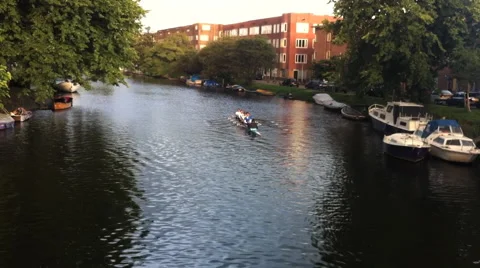 Athletes on a crew boat row down a canal in Amsterdam in the Netherlands.  Stock Footage 67836313